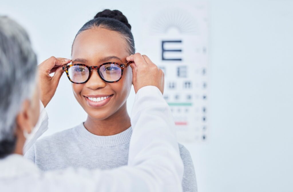 An optician fitting a patient with a new pair of glasses after their comprehensive eye exam.