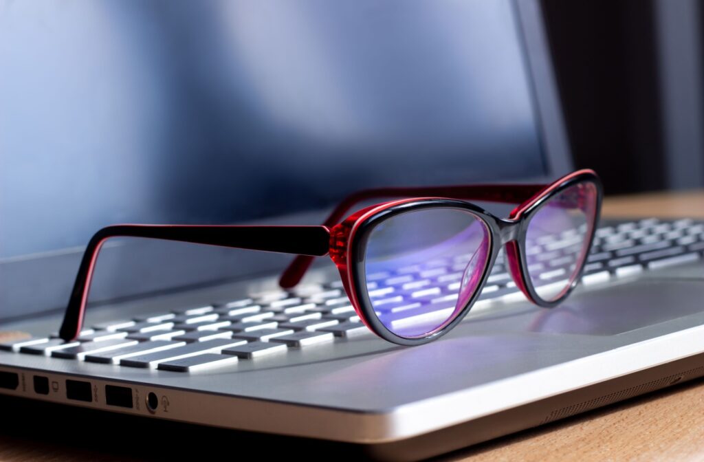 Red and black glasses sitting on top of a laptop.