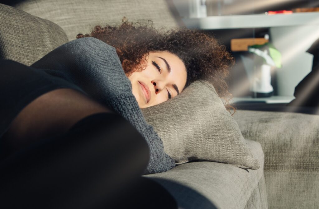 Person napping on a couch in sunlight emphasizing the risks of sleeping in contact lenses and eye health awareness