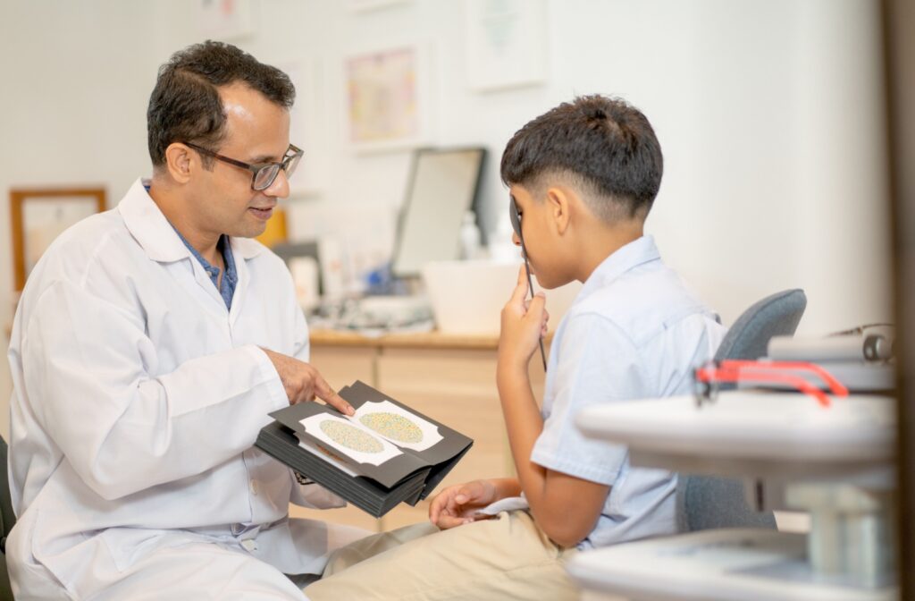 Child covering one eye while taking a color vision test with an optometrist during an eye exam