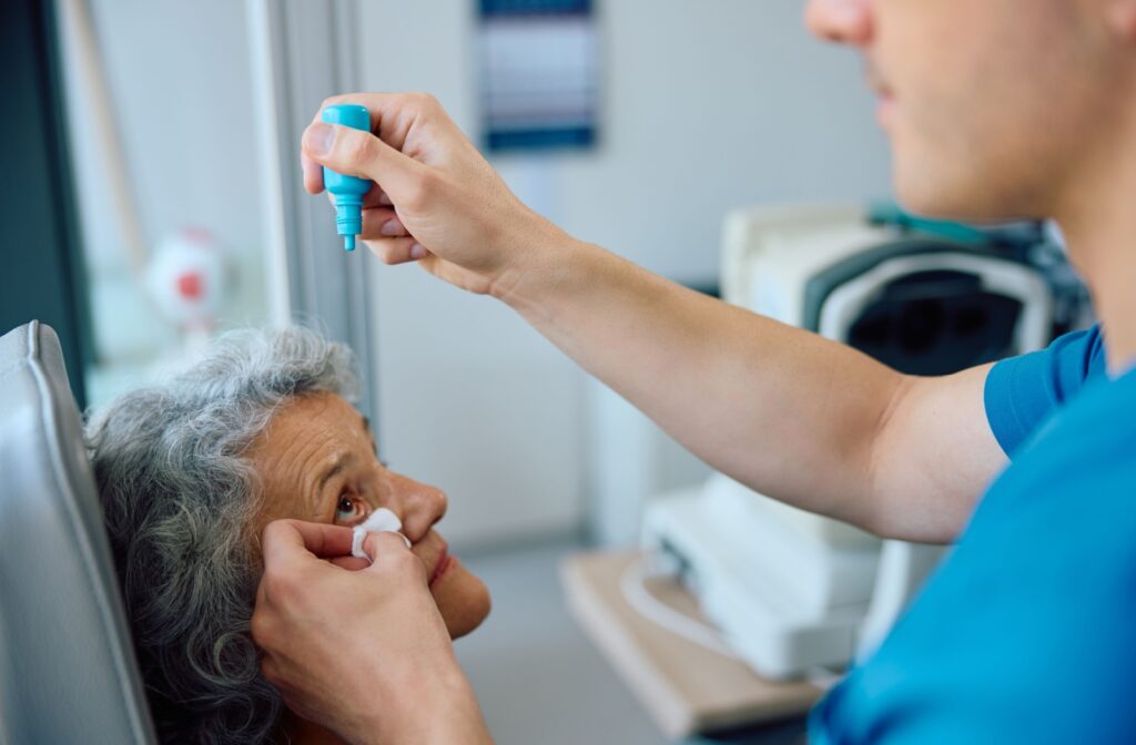 An optometrist administers eye drops for a patient's dilated eye exam.