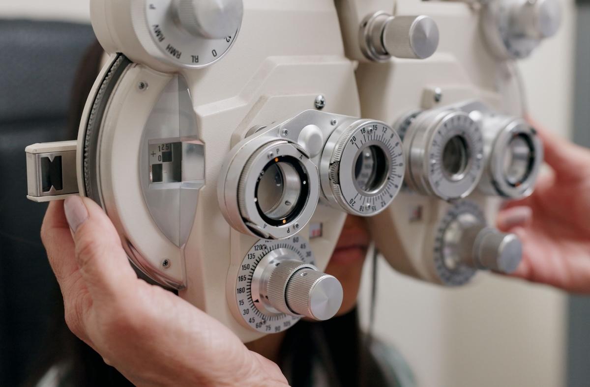 A patient having their eyes examined by an optometrist during an eye exam due to hazy vision issues.