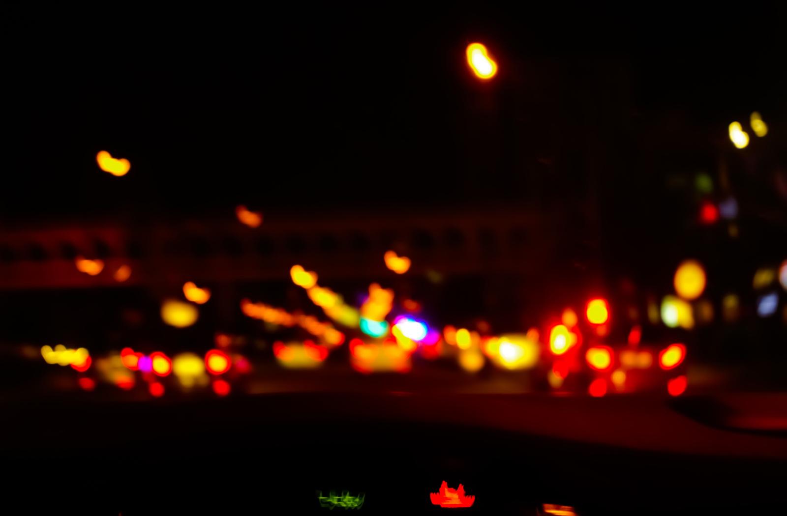 A point of view of blurry vision while driving at night, showing fuzzy street lights.